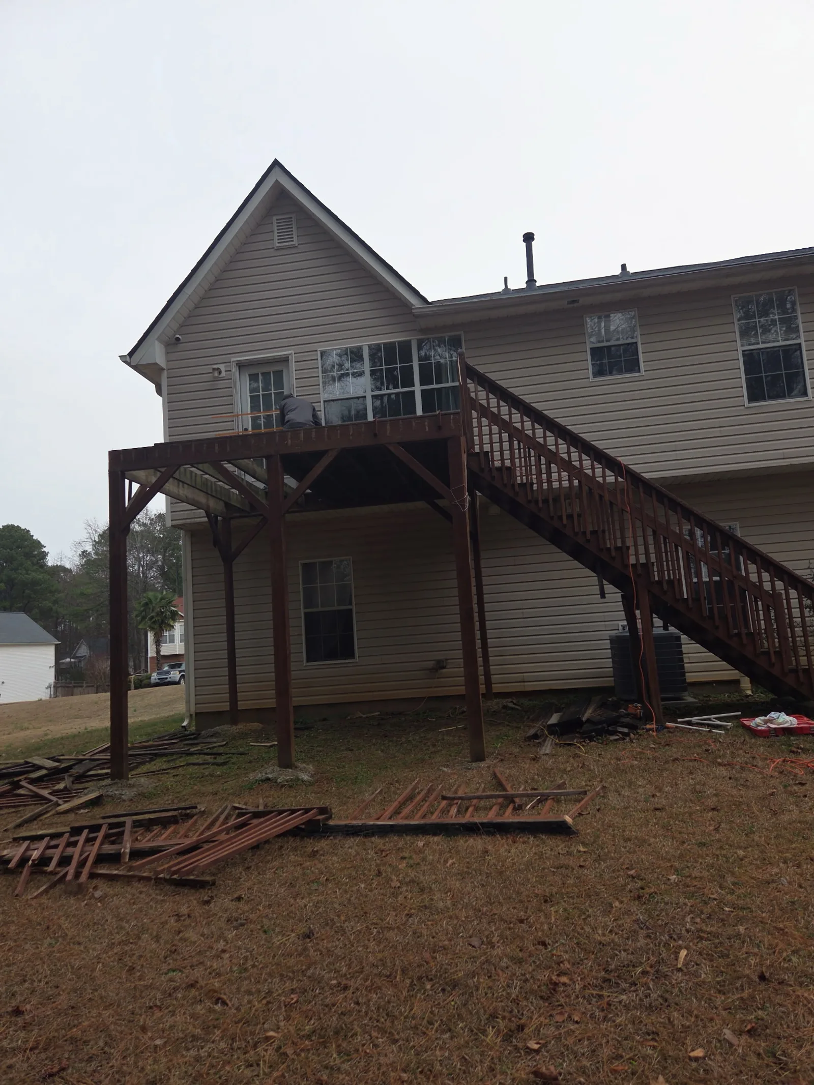 The same deck before the work: the old dark-stained deck half taken down, its boards on the lawn