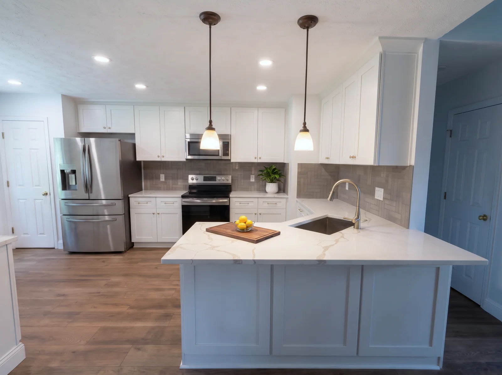 The kitchen from the living area: fridge, range and upper cabinets behind the quartz peninsula