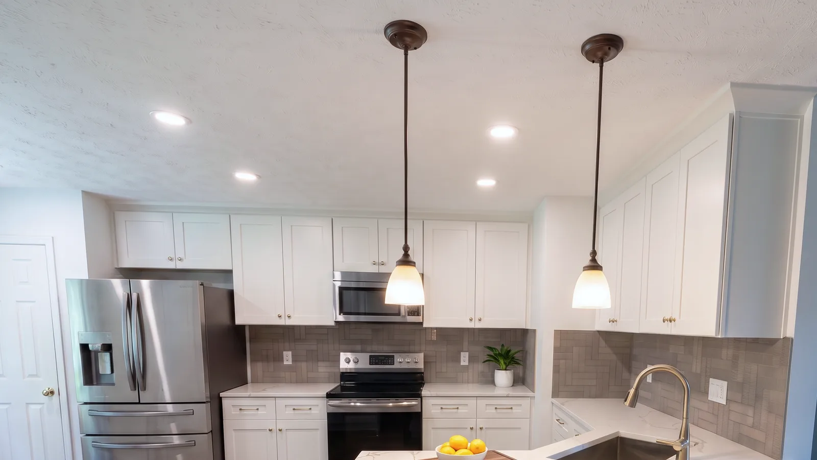 Two bronze pendants over the peninsula, with the upper cabinets and backsplash behind