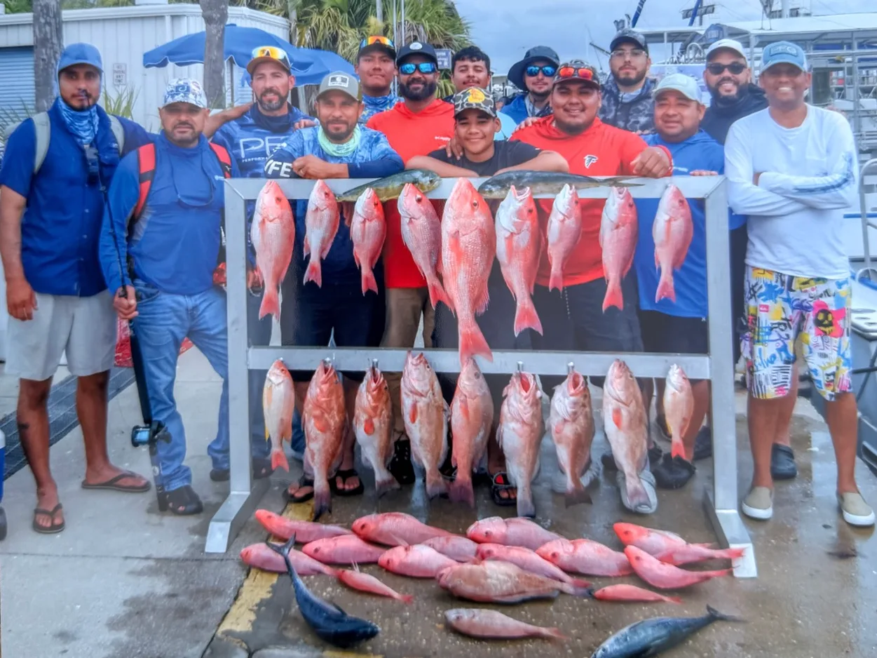 The Leoysa crew standing behind a rack of red snapper on a dock after a company fishing trip